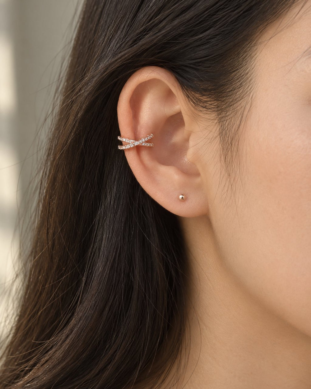 Close-up of the rose gold-tone cuff on the middle of a woman's ear, hair tucked back