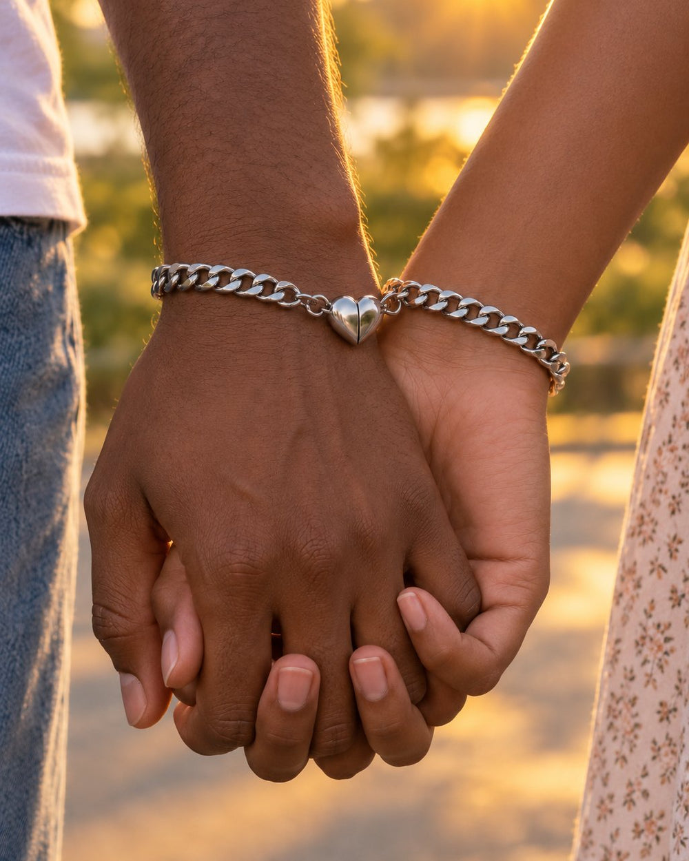 Two people hold hands, the heart halves on their bracelets joined into one heart between their wrists
