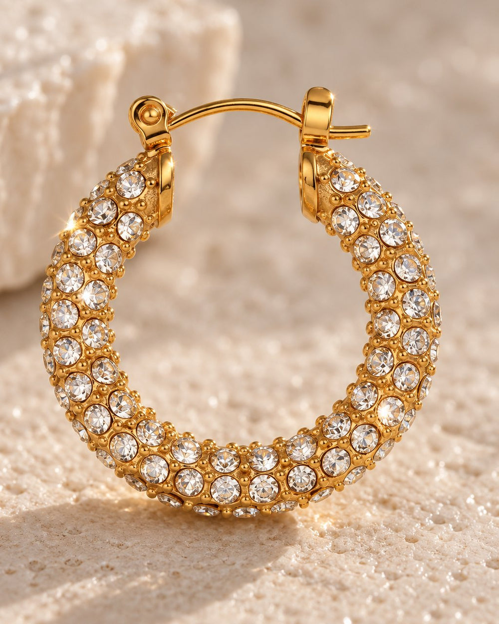 Close-up of the clear stones set around the gold-tone hoop and its hinged latch
