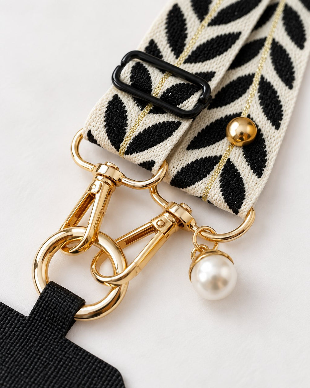 Close-up of the gold-tone swivel clasps, the faux-pearl charm and the leaf weave of the strap