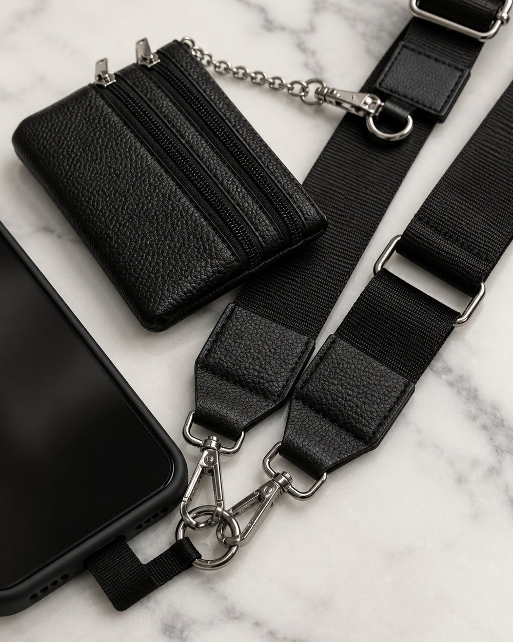 Close-up of the swivel clasps clipped to the tab at the bottom of a phone case, and the double-zip pouch