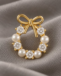 Close-up of the gold-tone bow, the claw-set clear stones and the round pearl-look beads