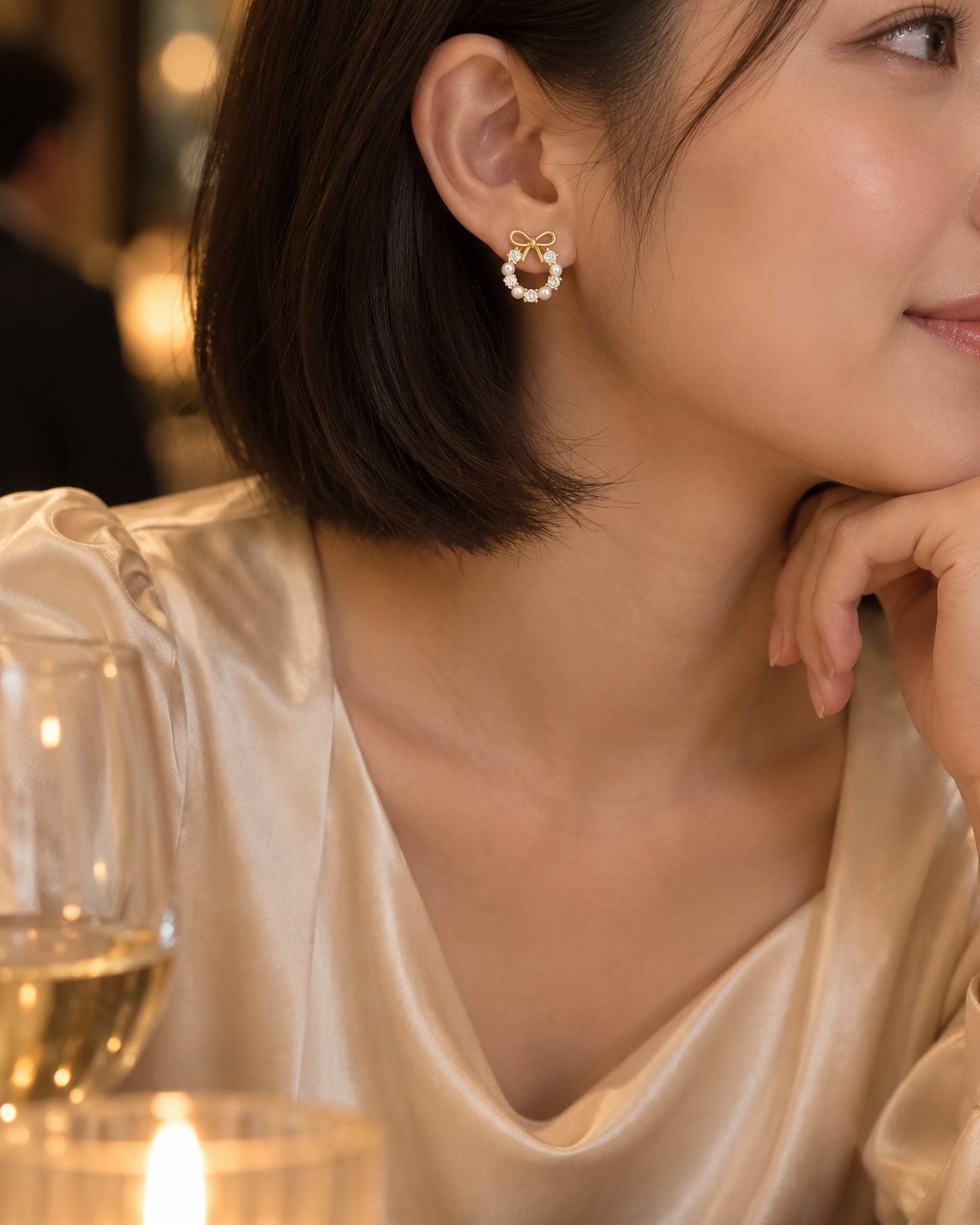 Woman with a short bob tucked behind her ear wearing a small bow and pearl-look wreath stud