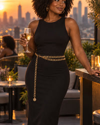 Woman in a black dress at an evening rooftop bar, the gold chain belt at her waist