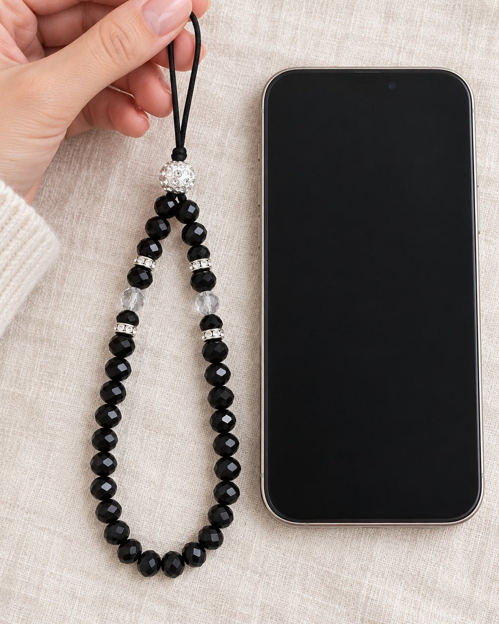 The beaded strap held up in one hand next to a phone, showing its length