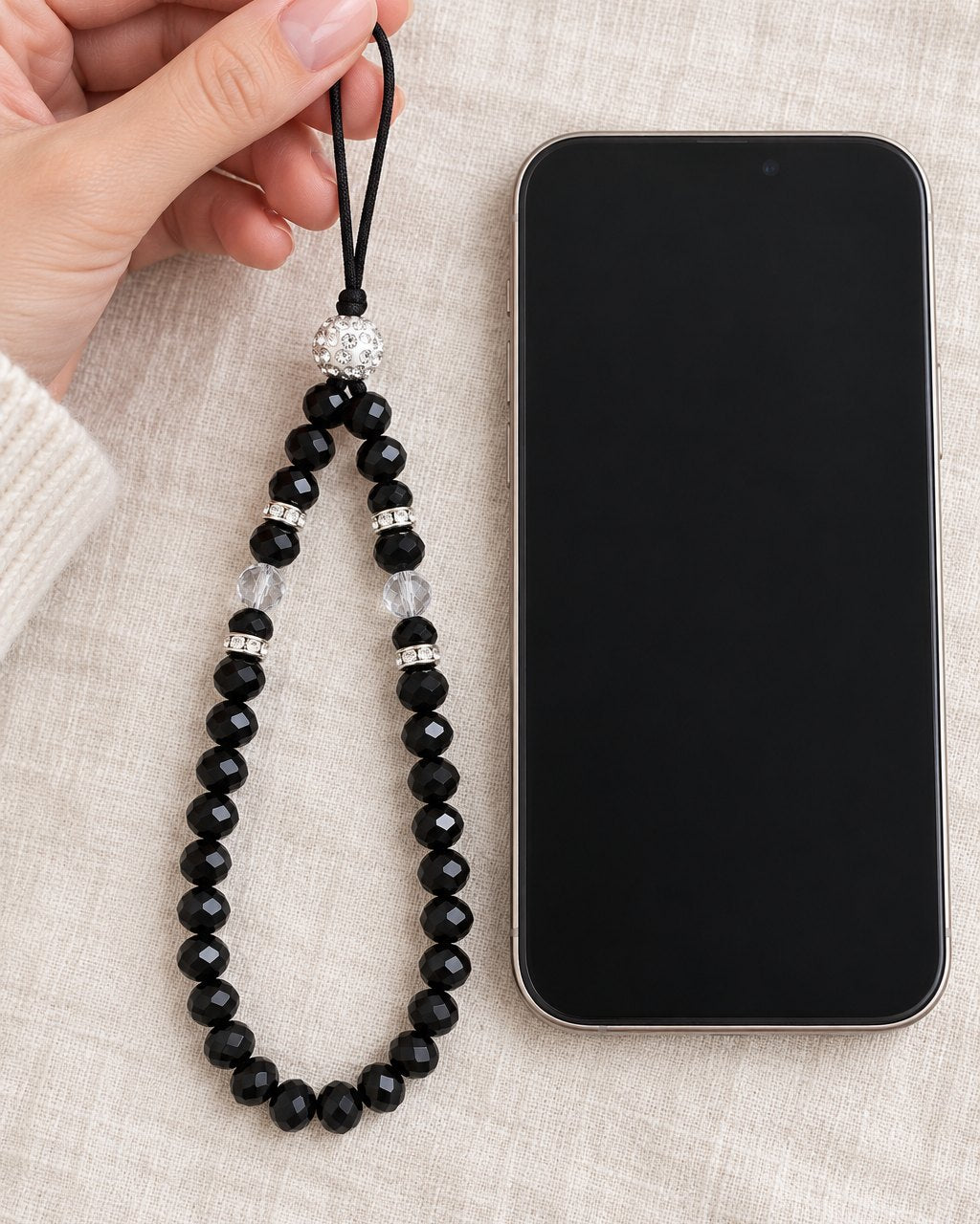 The beaded strap held up in one hand next to a phone, showing its length