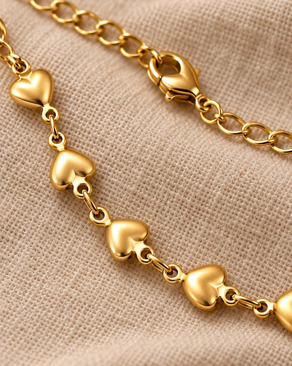 Close-up of the smooth puffed hearts, the small links and the lobster clasp
