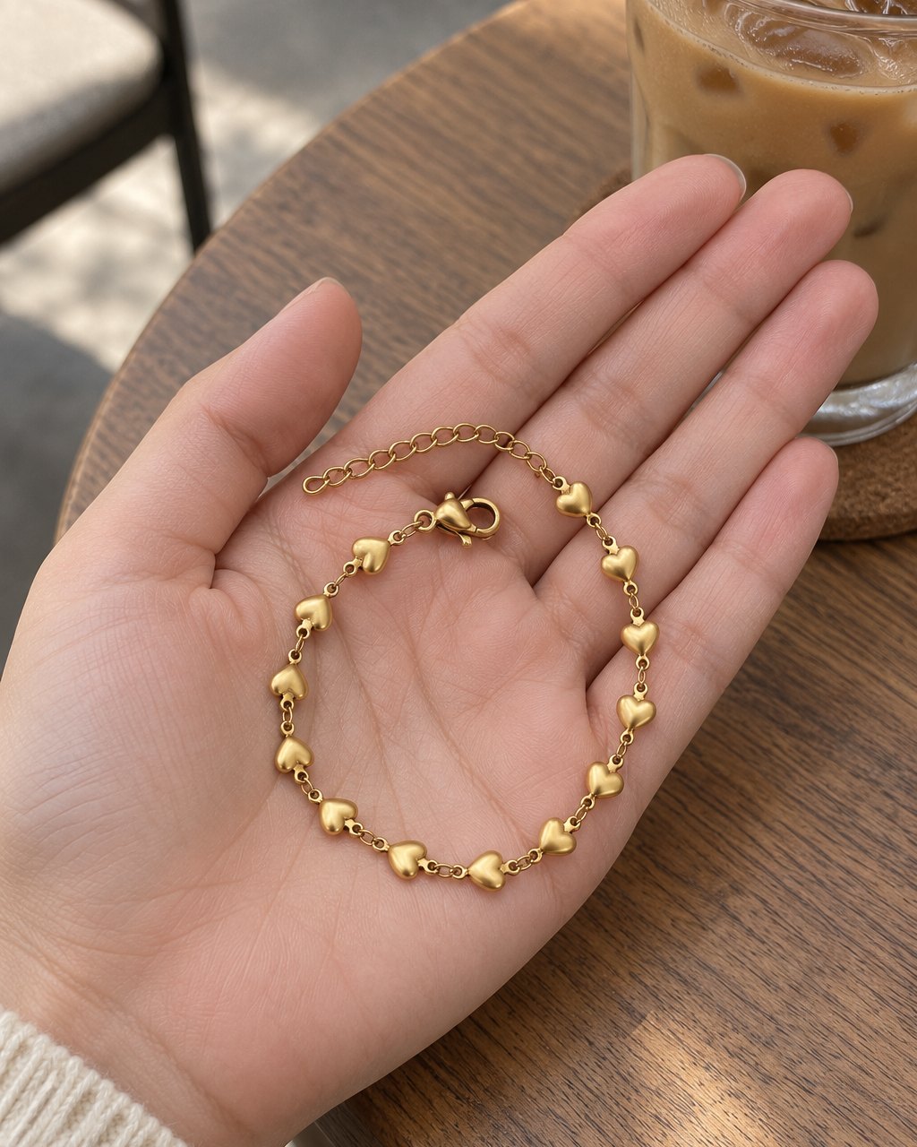 The heart anklet coiled in an open palm, each heart smaller than a fingertip