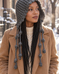 Woman on a frosty city street wearing the grey knit bonnet over long hair and a wool coat