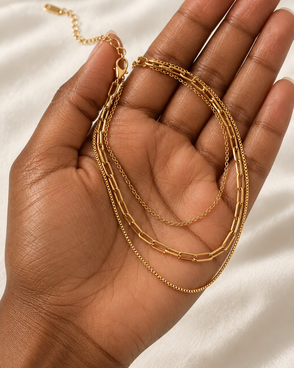 The layered necklace pooled in an open palm, showing its fine chains