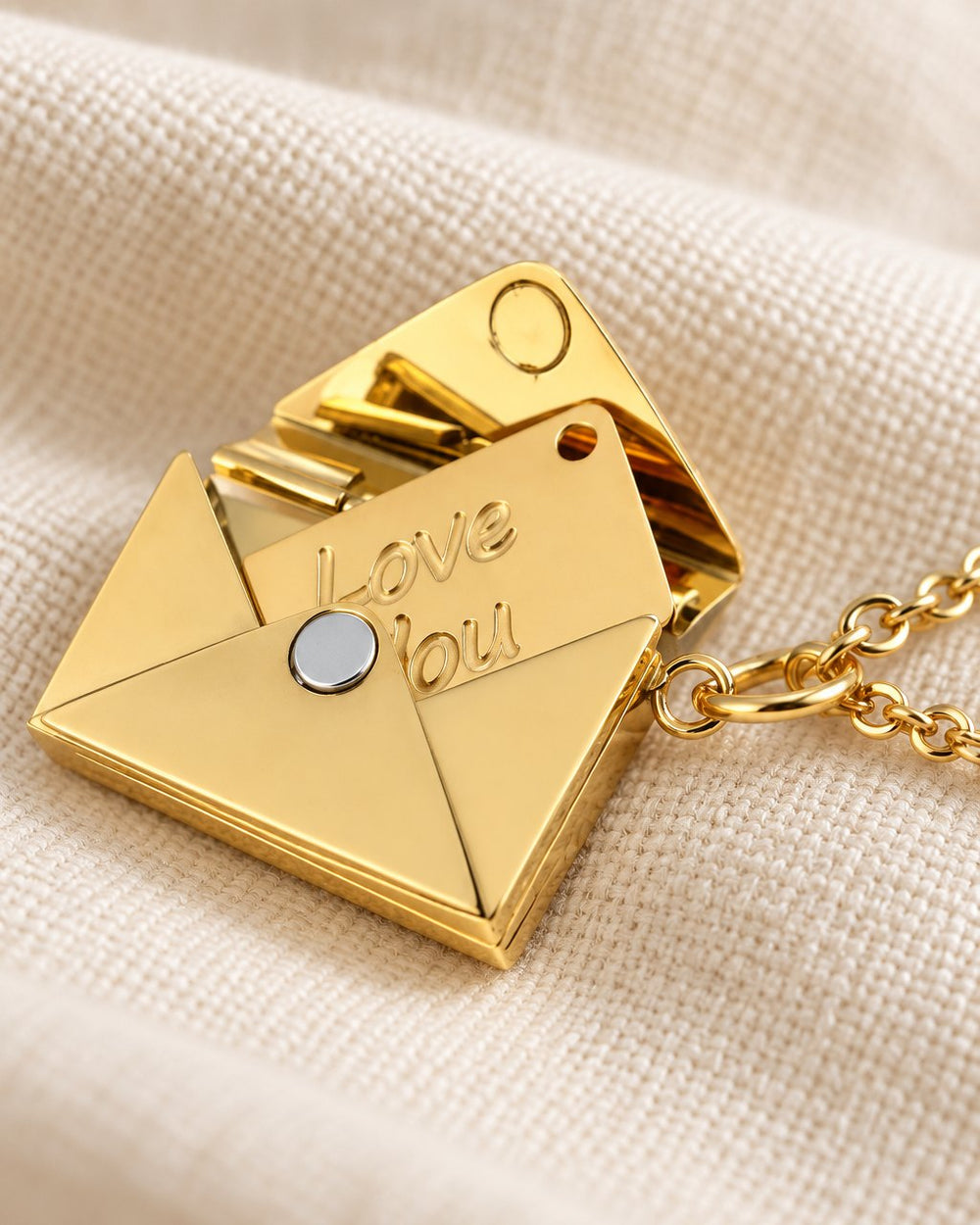 Close-up of the open envelope pendant and its small card engraved 'Love You' in script