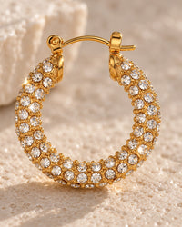 Close-up of the clear stones set around the gold-tone hoop and its hinged latch