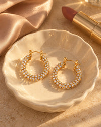 The pavé hoops in a cream ceramic dish on a vanity beside a lipstick