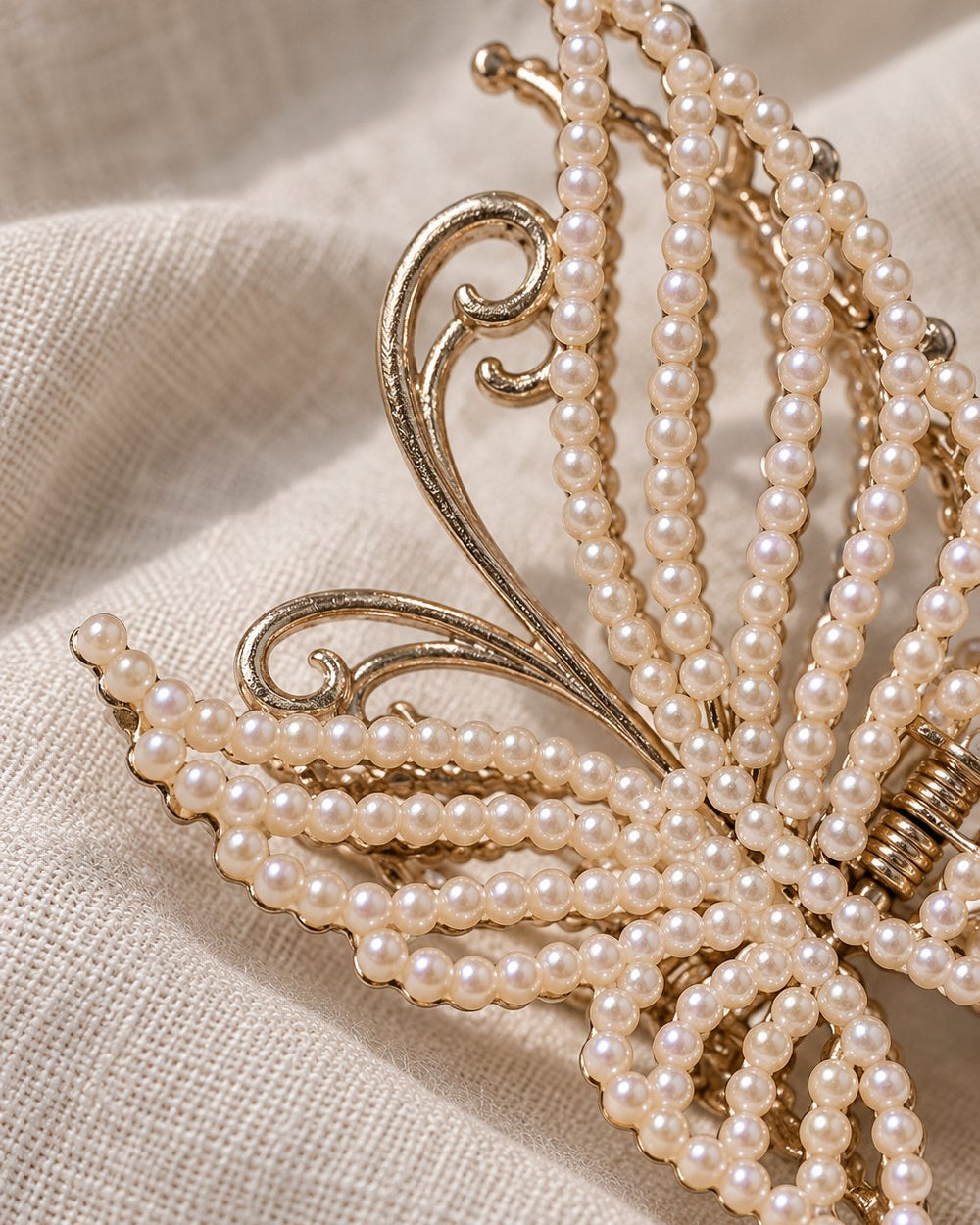 Close-up of the gold-tone wire wings and rows of small faux pearls on the butterfly clip