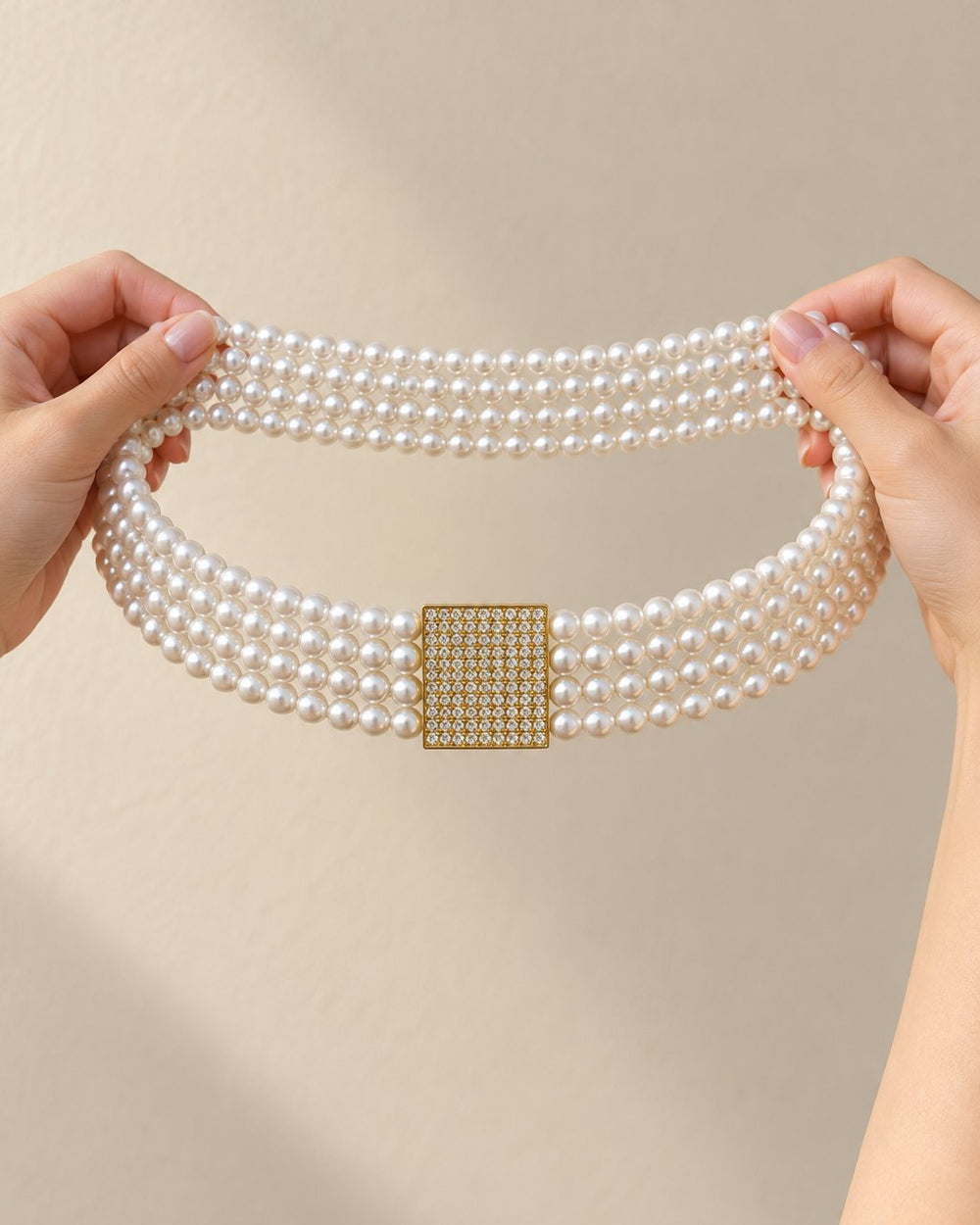 The pearl belt held up in a loop between two hands, showing all four rows