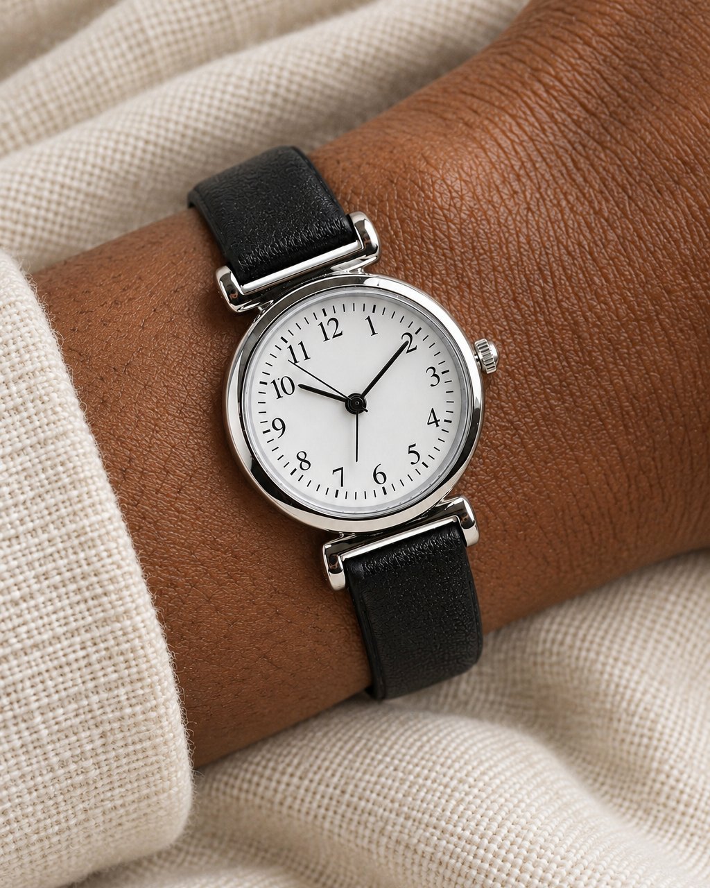 Close-up of the white dial with black numbers 1 to 12, slim hands and the small crown