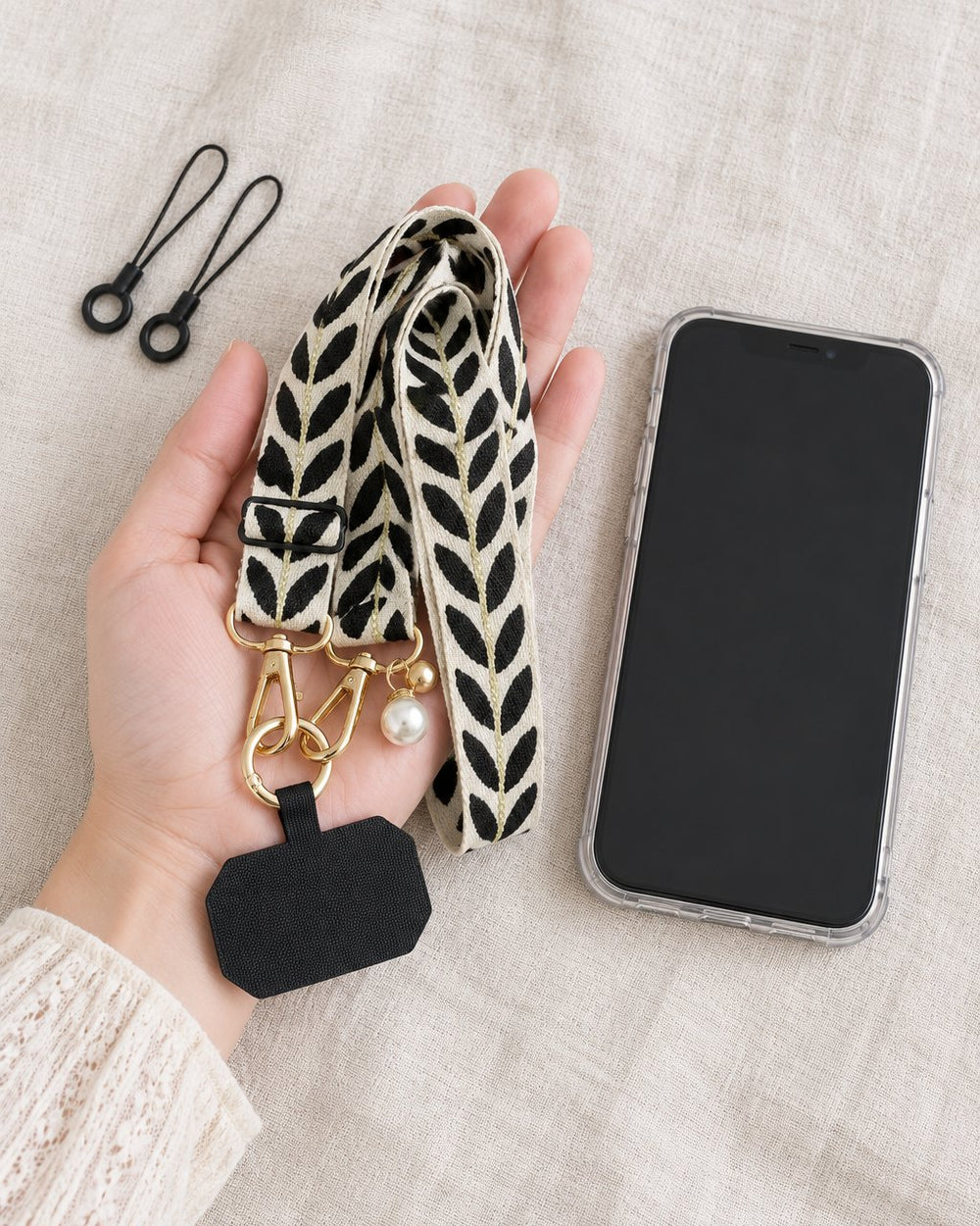 The woven strap loosely coiled in an open hand beside a phone in a clear case