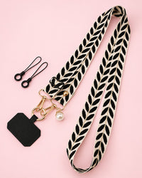 Cream woven phone strap with a black leaf pattern, gold-tone clasps, a faux-pearl charm and a black phone tab