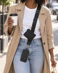 Woman walking with a coffee, the black strap worn crossbody and her phone hanging at her hip