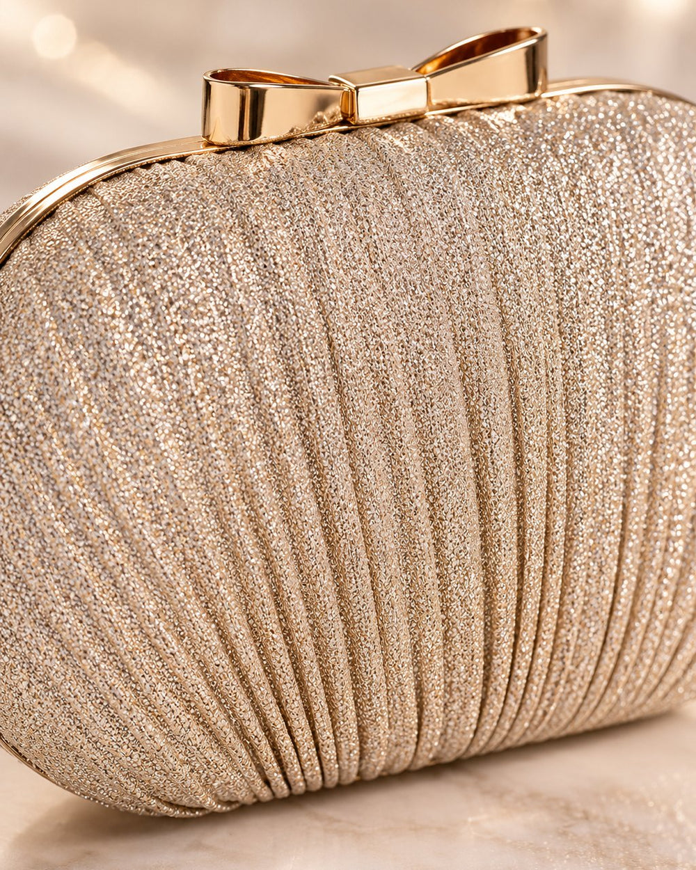 Close-up of the clutch's fine shimmering pleats, gold-tone frame and bow