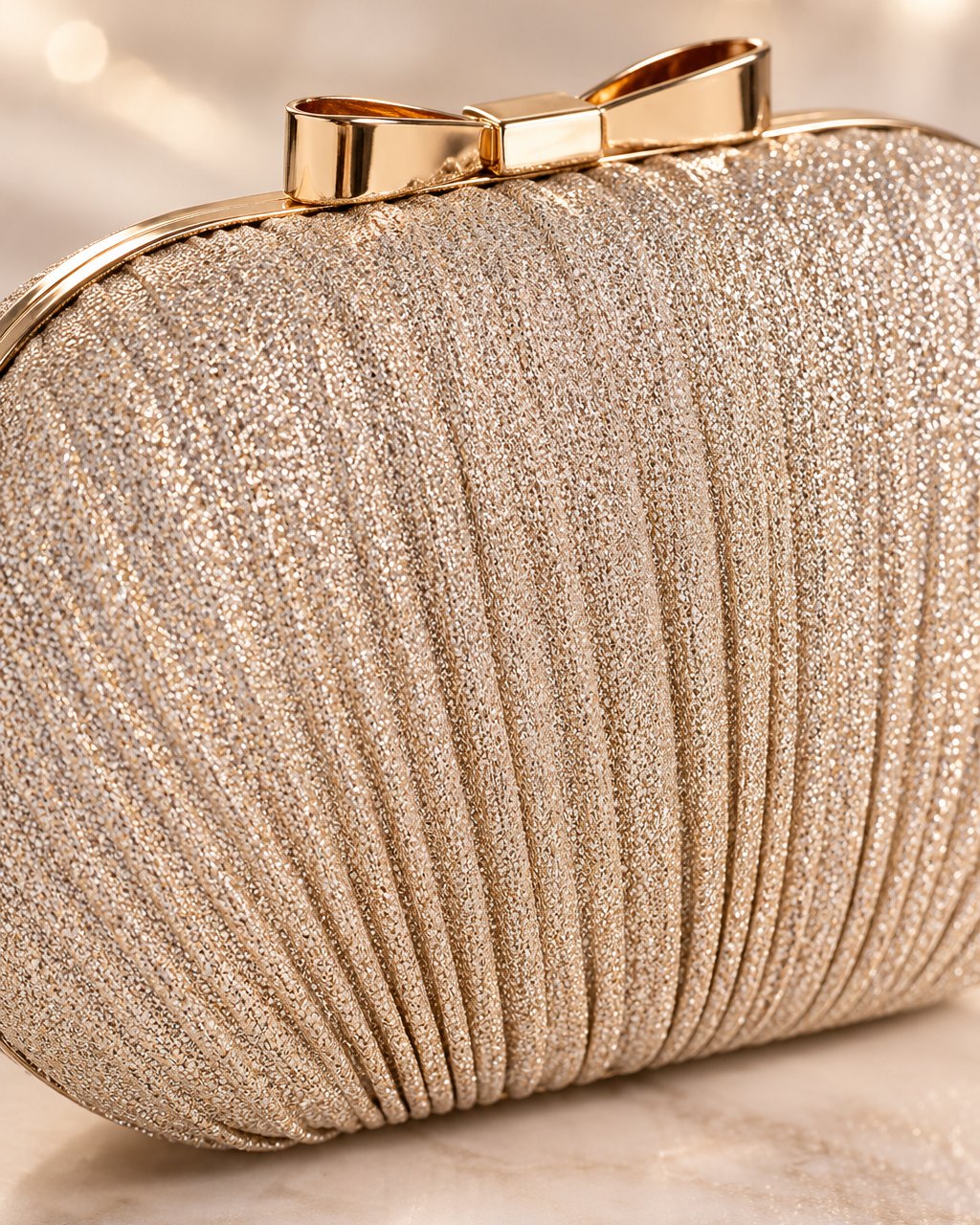 Close-up of the clutch's fine shimmering pleats, gold-tone frame and bow