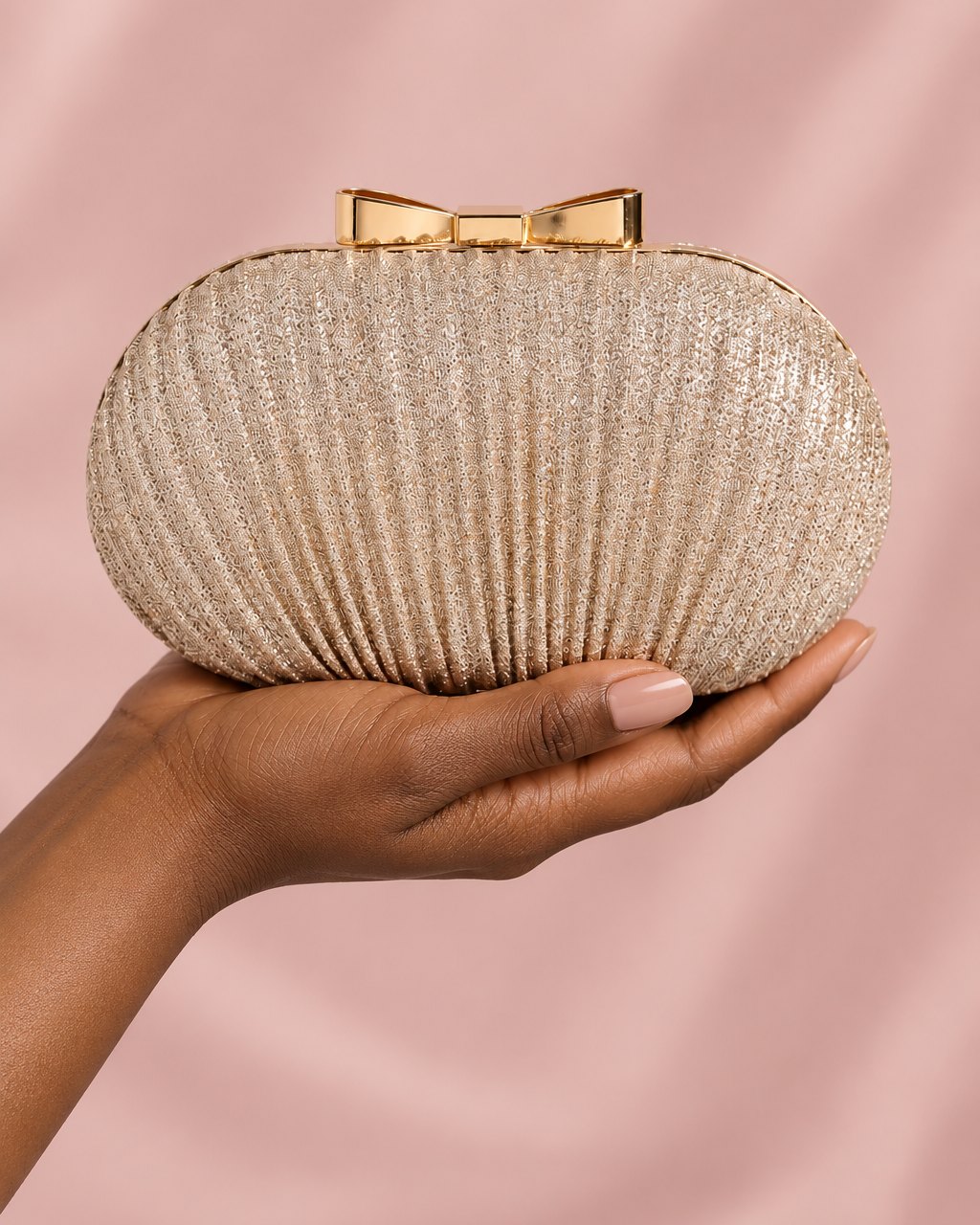 The pleated clutch held in one hand, showing its small evening size