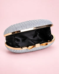 Silver-tone pleated clutch, open to show the black lining, with a gold-tone frame and bow