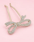 Two-prong hair pin topped with a ribbon bow paved in clear rhinestones