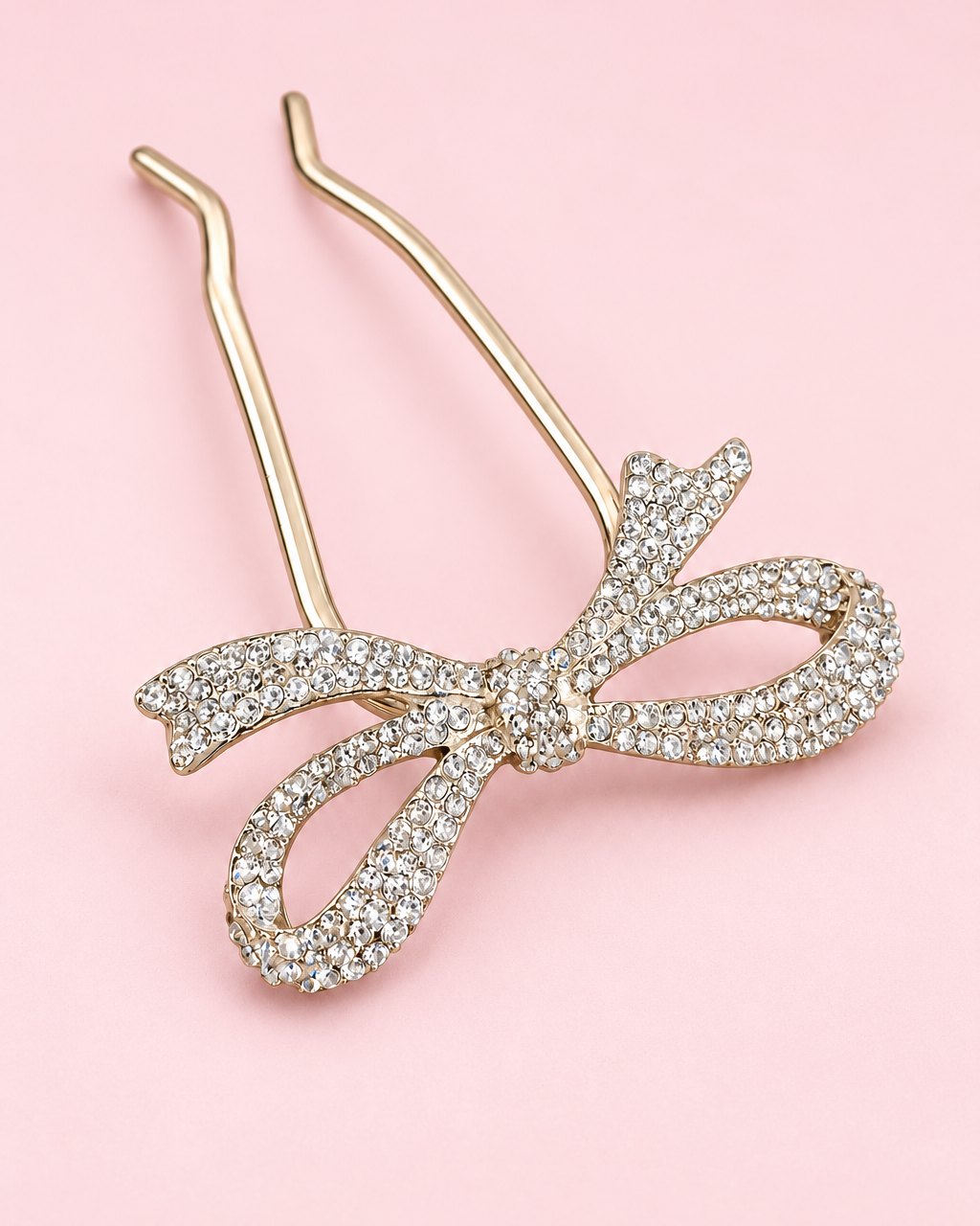 Two-prong hair pin topped with a ribbon bow paved in clear rhinestones