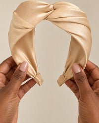 The twist headband held in two hands, showing the wide knot at the top