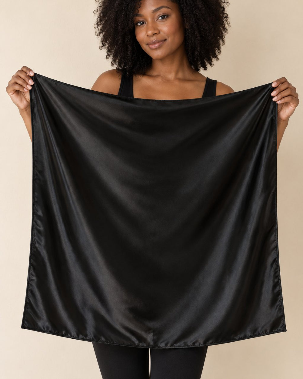 The black satin scarf held open by two corners, a large 90 cm square reaching from shoulders to hips