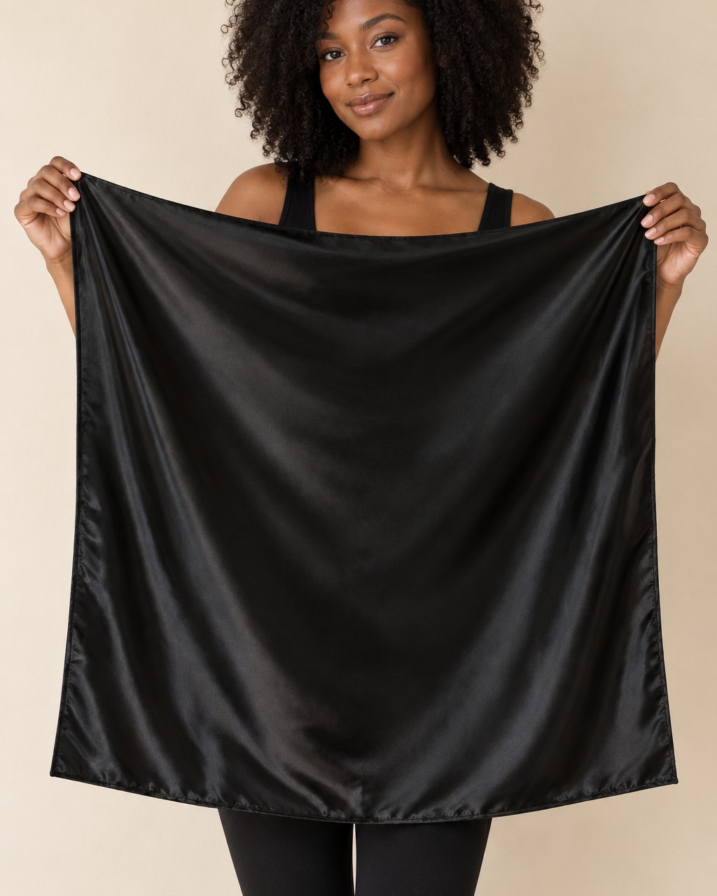 The black satin scarf held open by two corners, a large 90 cm square reaching from shoulders to hips