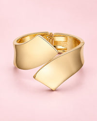 High-shine gold-tone cuff with two sculpted ends crossing over each other