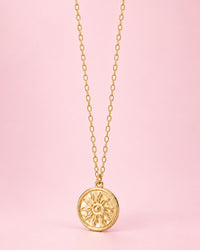 Gold-tone round coin pendant with an embossed sun on a fine chain