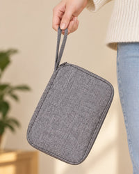 The closed grey cable pouch held in one hand by its wrist loop, smaller than a tablet