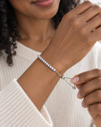Woman pulling the ball-tipped ends to tighten the bracelet on her wrist