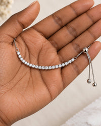 The bracelet resting in a loose loop on an open palm, its 8 cm row of stones across the palm