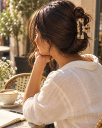 Woman at a café table with her hair in a loose twist held by the tortoise claw clip